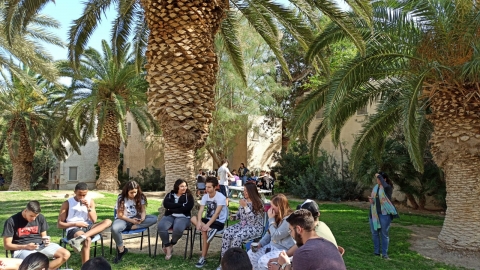 נערים ונערות יושבים על מדשאות קיבוץ עין גדי