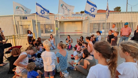 אנשים וילדים יושבים בכניסה לגן, פתיחת הגנים בהר עמשא
