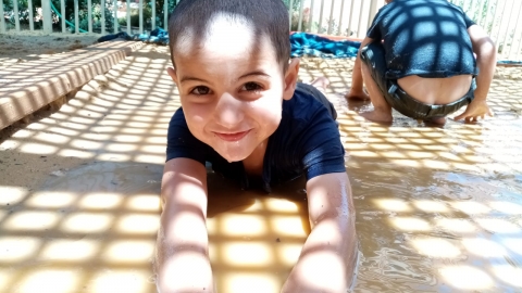 ילד קטן שוכב על בוץ ומחייך