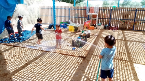 ילדים משחקים בחצר מוצלת בקיץ עם מים