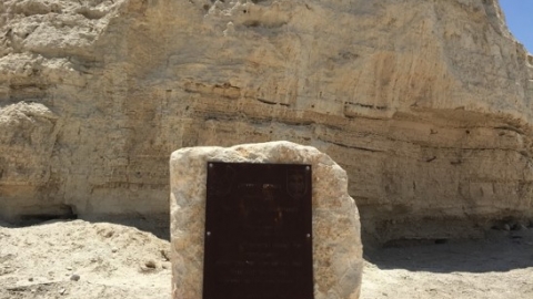 ראשית ההתיישבות בכיכר סדום, אנדרטה מאבן בז' ועליה תלוי שלט חום כהה מברזל
