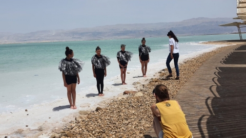 רקדניות לבושות שחור מצטלמות על חוף הים